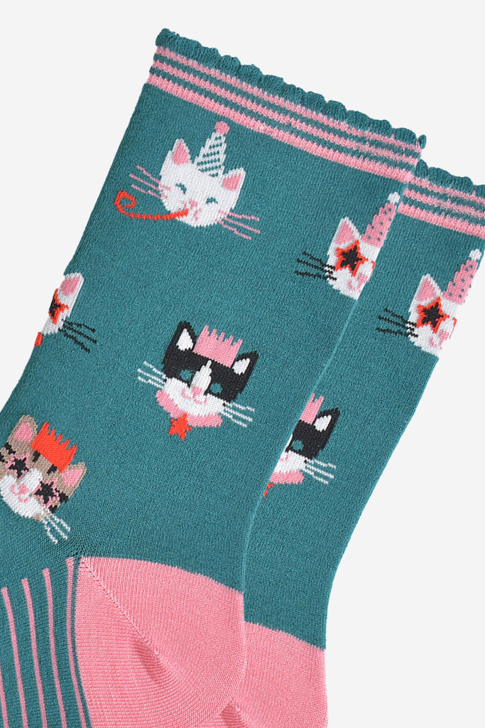 close up of the cat design on the socks, there is a white cat wearing a party hat and blowing a party trumpet, a white cat with a party hat wearing star shaped sunglasses, a black and white cat wearing a pink party crown and a tabby cat wearing a party crown and glasses.