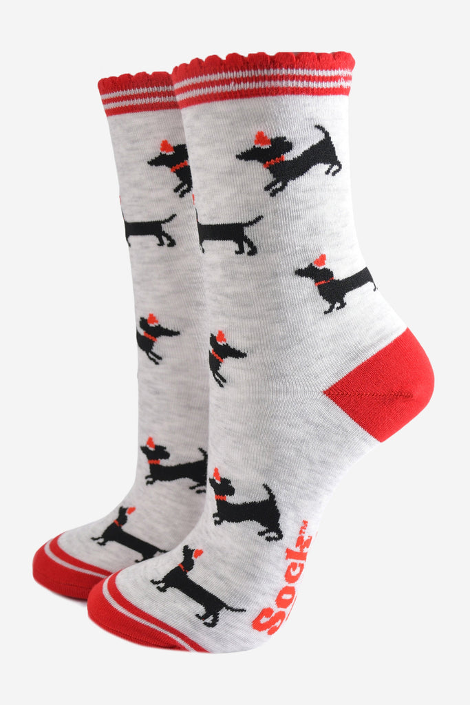 light grey socks with red heel, toe and scalloped cuff with an all over pattern of black sausage dog silhouettes wearing red santa party hats