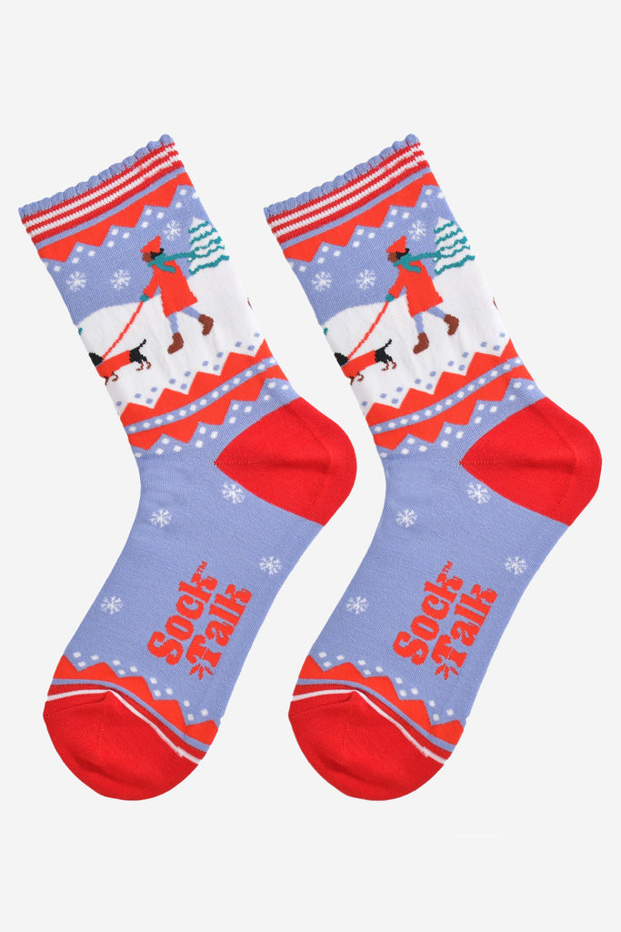 showing the sausage dog socks laying flat, there is a pattern of white snowflakes throughout the design, on the ankle of the socks the sausage dog design is prominent