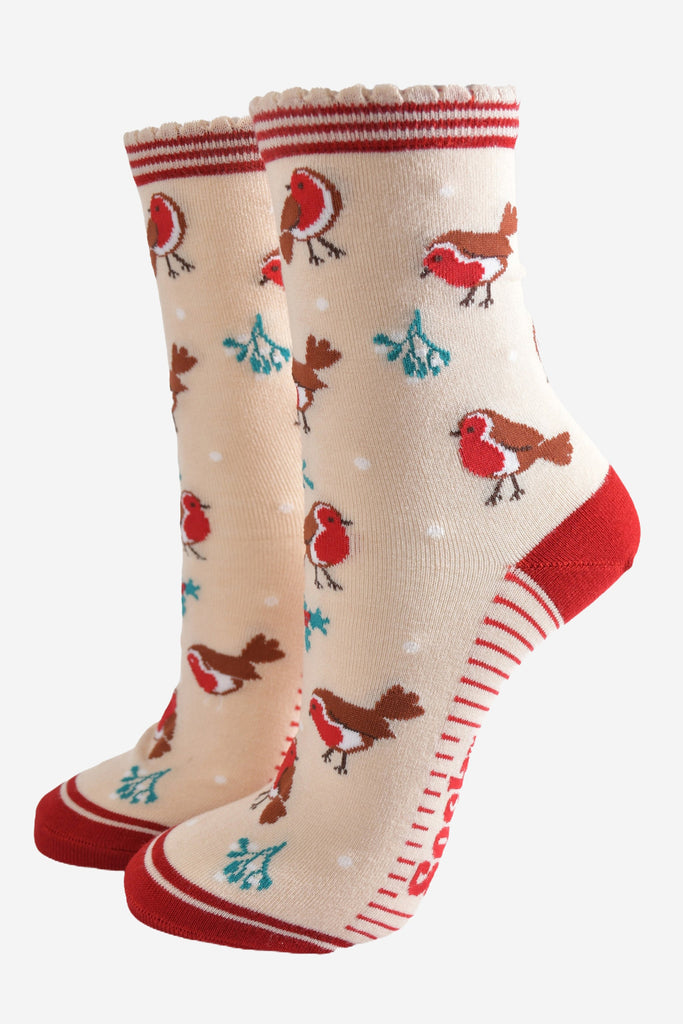 cream socks with a red striped cuff with a pattern of red robin birds, mistletoe and holly all over