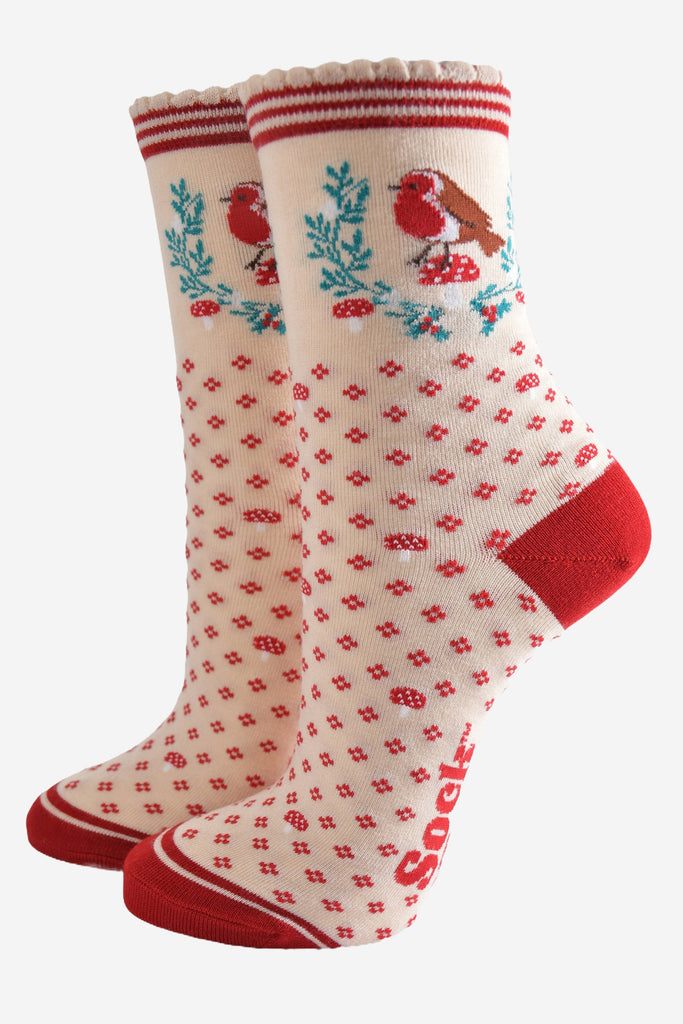 cream and red ankle socks with a red heel, toe and striped cuff, with a red robin perched on a red toadstool surrounded by a festive holly wreath.