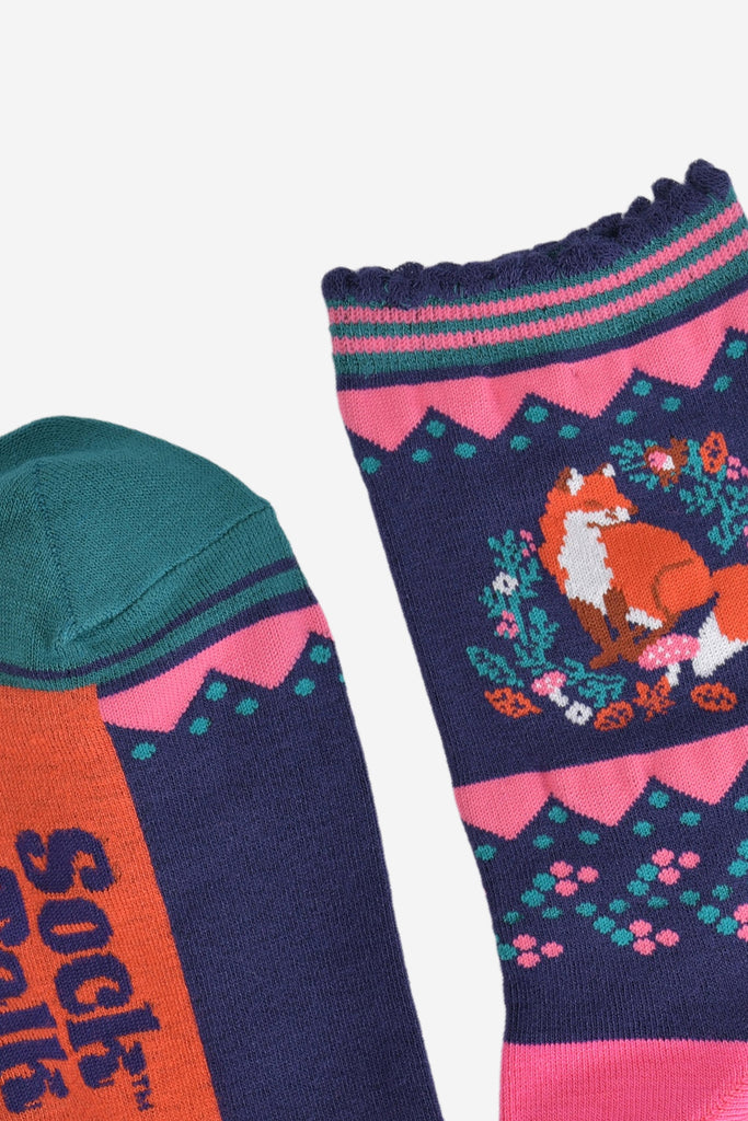 close up of the cuff and toe of the socks, the toe is green with a navy blue striped edge, the cuff is scalloped and had pink and green contrasting stripes