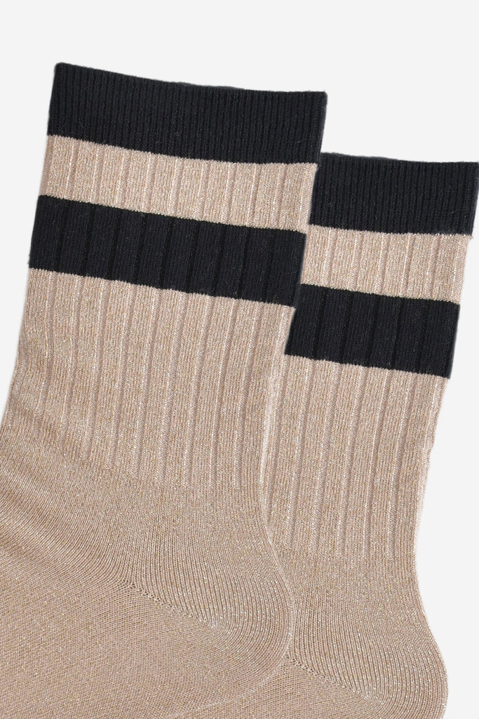 close up of the ribbed sports style cuffs on the socks. they have vertical ribbed details. the base of the socks are gold with a glitter sparkle. the cuff is black and there is a horizontal black band stripe, without glitter an inch below the cuff. 