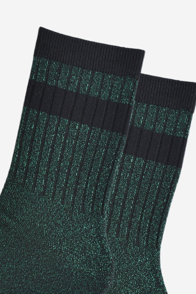 close up of the ribbed sports style cuffs on the socks. they have vertical ribbed details. the base of the socks are green with a silver glitter sparkle. the cuff is black and there is a horizontal black band stripe, without glitter an inch below the cuff. 