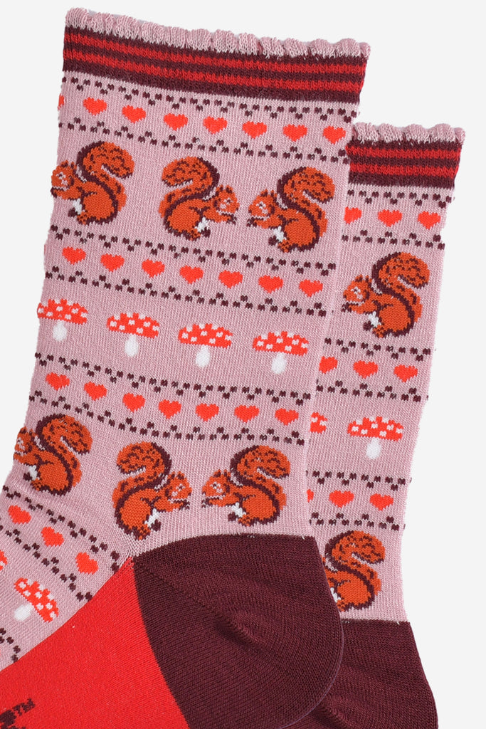 close up of the red squirrels, red love hearts and red toadstool fair isle pattern on the pink bamboo socks