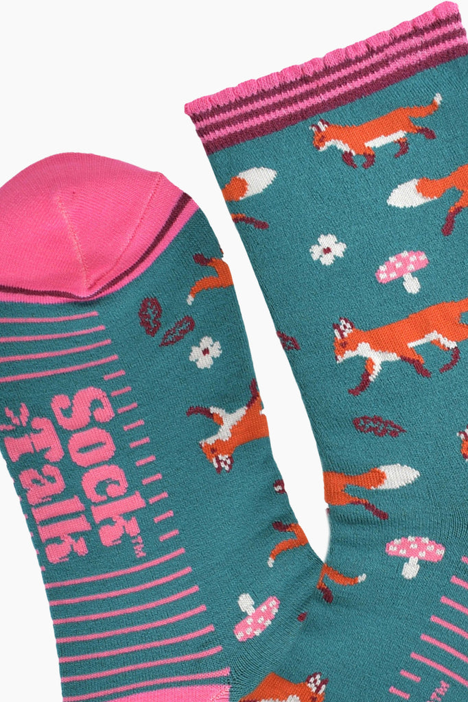 close up of the toe and cuff, the toe is pink with a thin burgundy stripe, the cuff is scalloped and also pink and burgundy striped, the sole of the socks have pink stripes on them