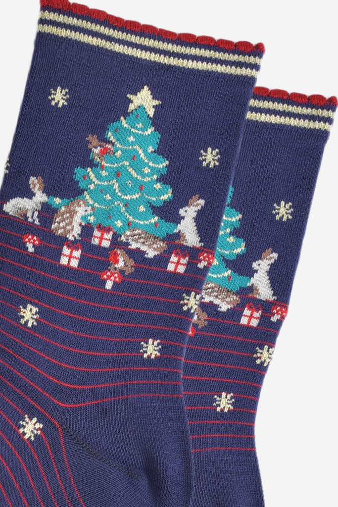 close up of the christmas tree design on the ankle of the socks, there are rabbits, hedgehogs, robins, toadstools and christmas gifts all around the tree