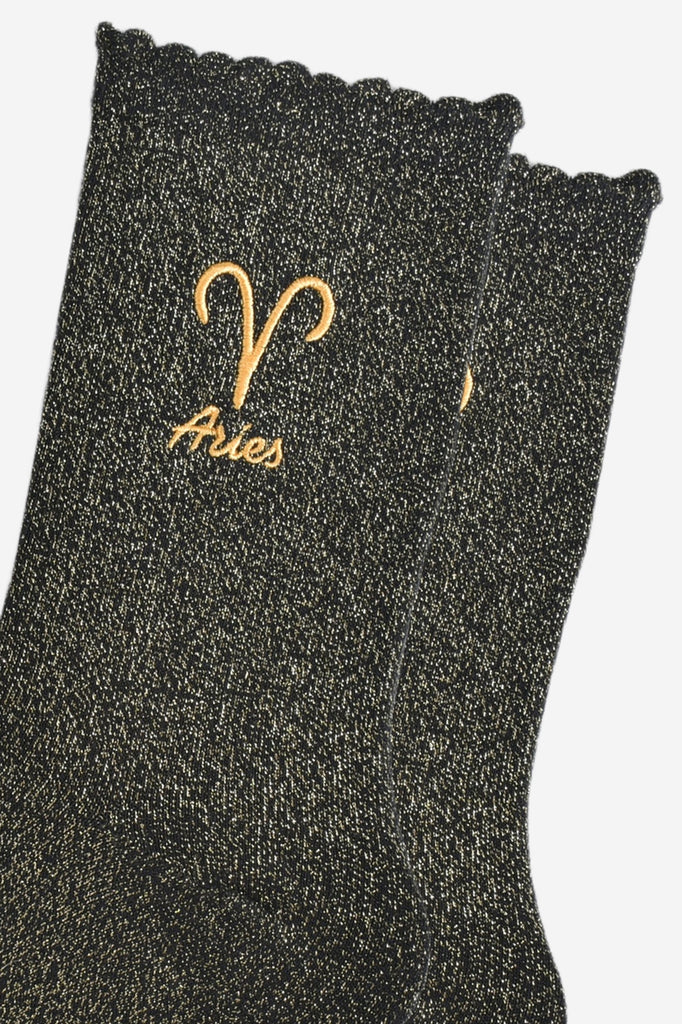 close up of the gold embroidered zodiac detail on the ankle of the socks, showing clearly the symbol of and word aries
