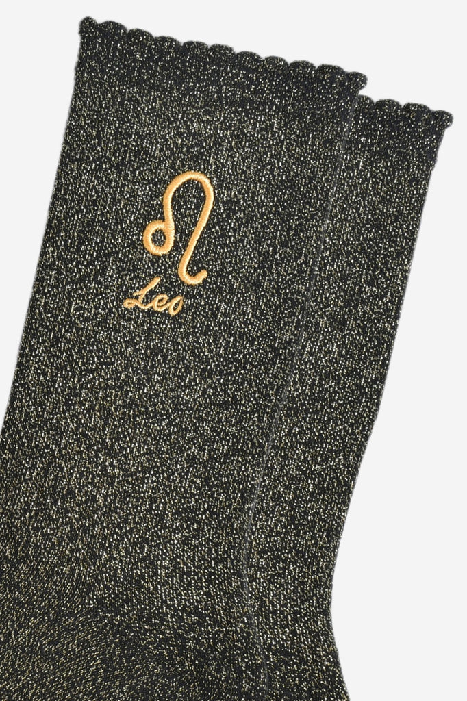 close up of the gold embroidered zodiac detail on the ankle of the socks, showing clearly the symbol of and word leo