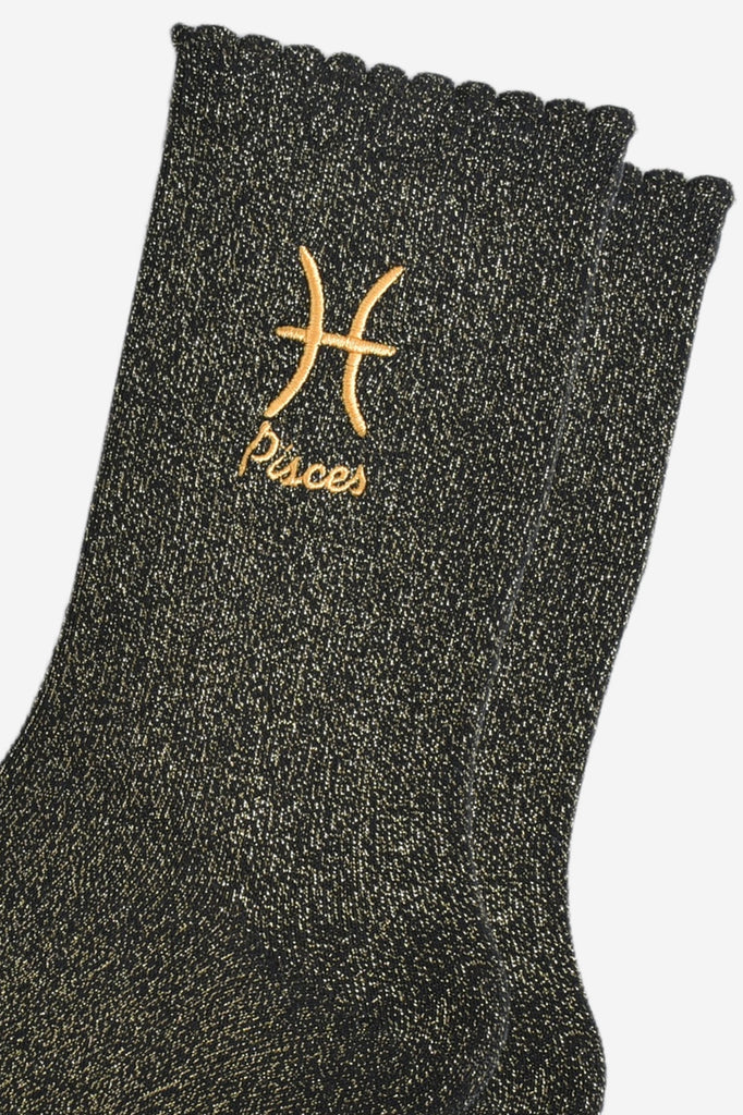 close up of the gold embroidered zodiac detail on the ankle of the socks, showing clearly the symbol of and word pisces
