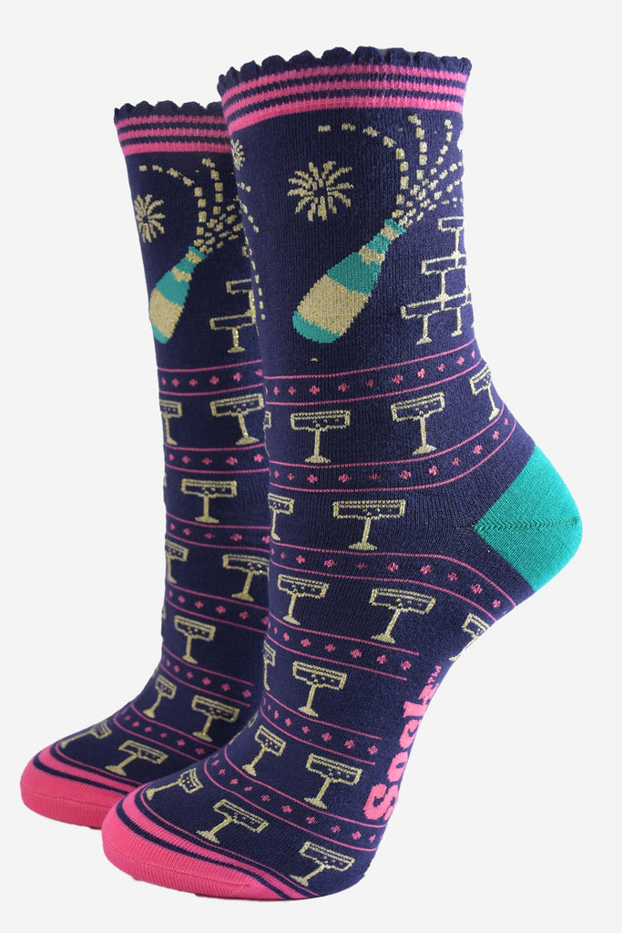 navy blue socks with a pattern of popping champagne bottles and vintage coupe glasses, the socks have a pink striped scalloped cuff 