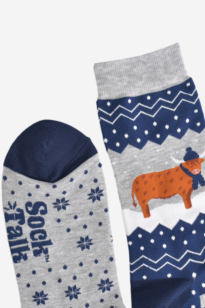 showing the toe and cuff of the socks, showing clearly the fair isle pattern and highland cow, the cow is wearing a winter hat and scarf