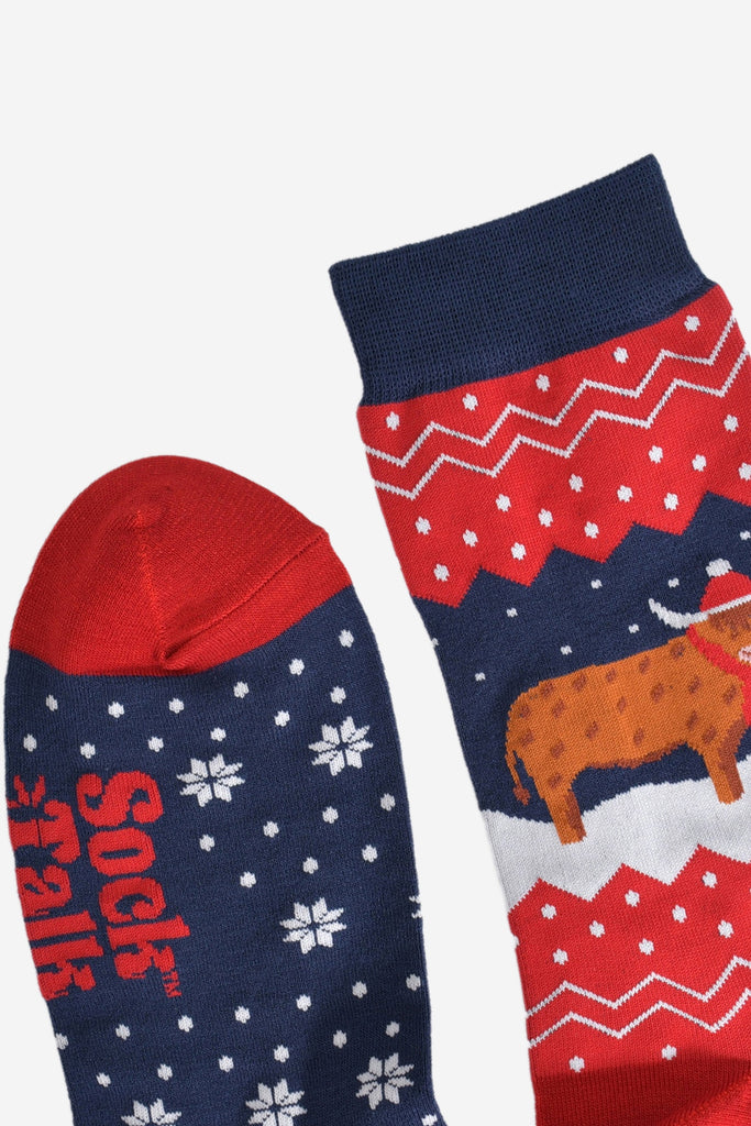 showing the toe and cuff of the socks, showing clearly the fair isle pattern and highland cow, the cow is wearing a winter hat and scarf