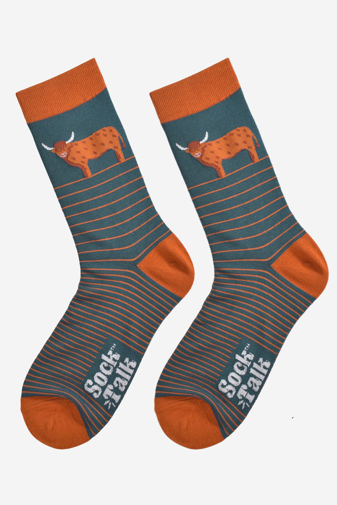 teal and orange striped bamboo socks laying flat, there is a large highland cow on the ankle of the sock, the cow is in profile and standing up