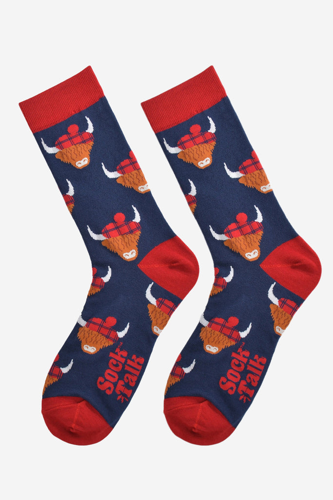 red and navy blue highland cow bamboo socks laying flat, the highland cows are wearing blue tartan hats