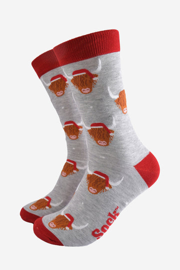 light grey socks with a red heel, toe and cuff with an all over pattern of highland cows wearing santa hats