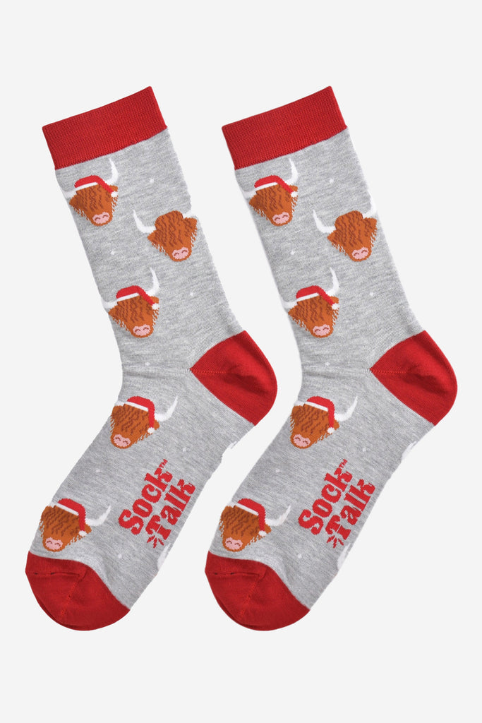 grey and red bamboo socks laying flat, showing the all over pattern featuring highland cows wearing red santa hats