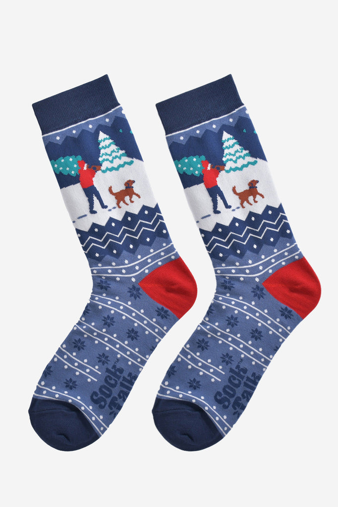 christmas man and dog socks laying flat, showng the blue fair isle pattern and festive winter dog walker scene