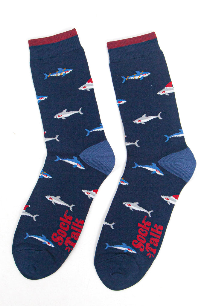 showing the shark socks laying flat, there is an all over pattern of swimming blue and grey sharks wearing festive hats and party lights