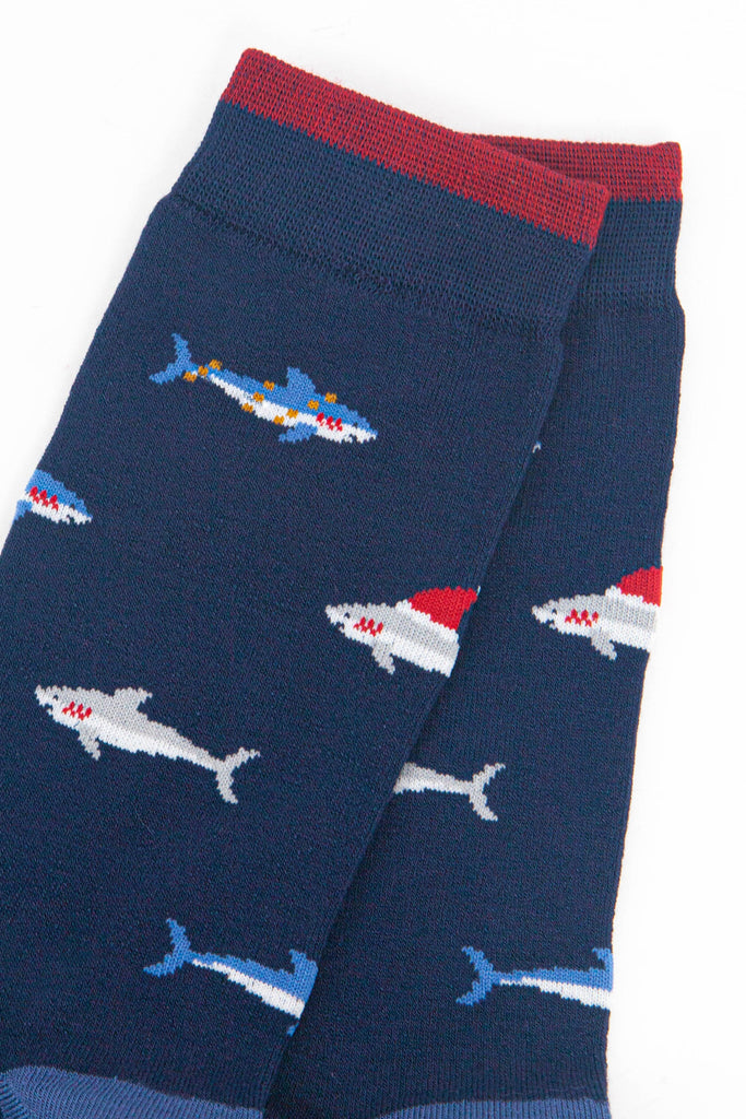 close up of the shark pattern, there are grey sharks wearing santa hats and blue sharks entangled in party lights