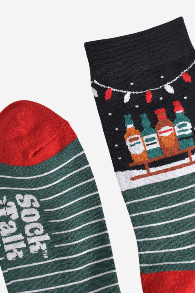 close up of the cuff and the toe of the socks, the toe is red in contrast to green of the socks, cuff is black in keeping with the winter night scene featuring the sledge and party lights