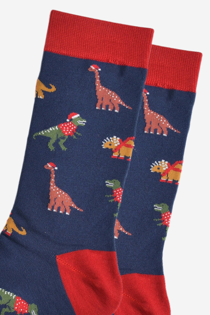 close up of the dinosaur design on the socks, t-rex, triceratops and brontosaurus are all wearing festive attire, santa hats and jumpers