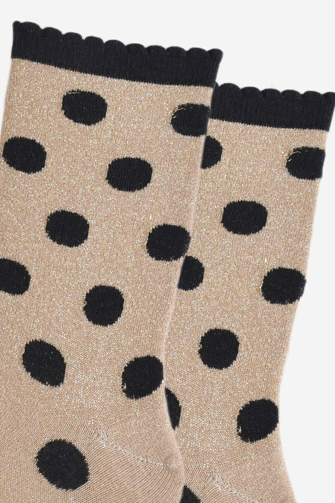 close up of the black polka dot pattern and all over silver glitter on the gold ankle socks