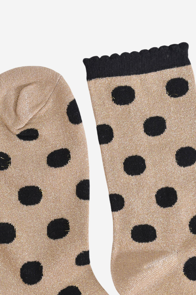 close up of the toe and cuff, the toe is gold with silver sparkles like the base of the socks, the cuff is black and has a scalloped edge