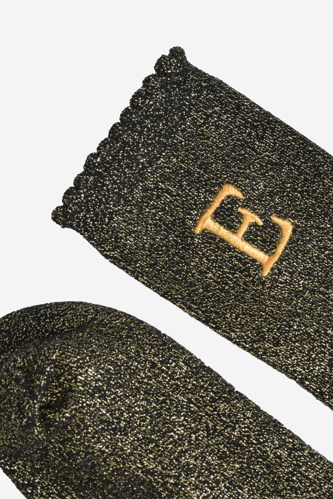 close up of the scalloped cuff on the socks, the toe is the same black and gold as the rest of the socks