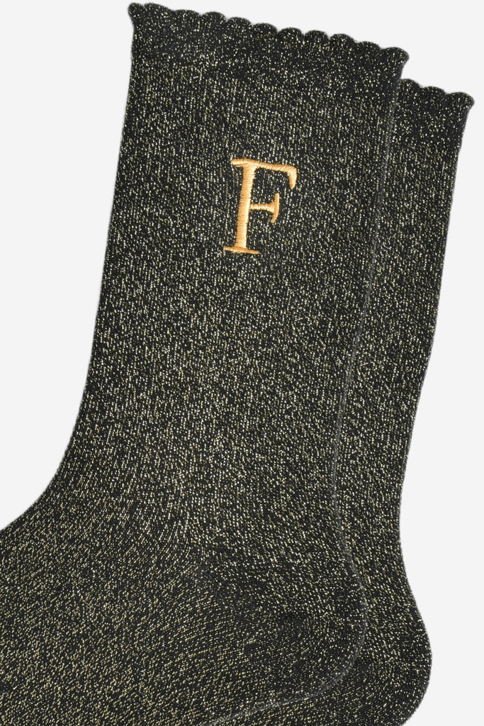 close up of the gold embroidered capital letter f on the ankle of the socks