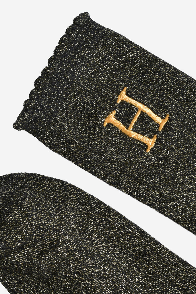 close up of the scalloped cuff on the socks, the toe is the same black and gold as the rest of the socks