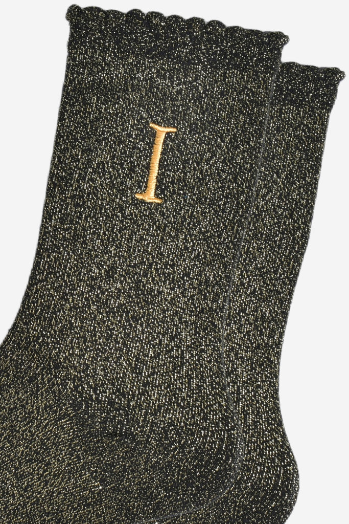 close up of the gold embroidered capital letter i on the ankle of the socks