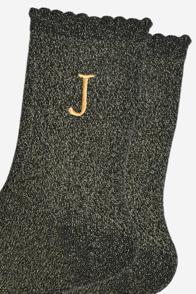 close up of the gold embroidered capital letter j on the ankle of the socks