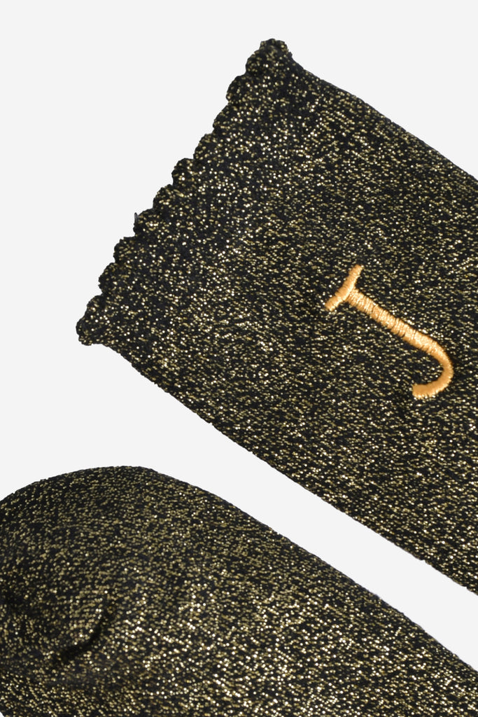 close up of the scalloped cuff on the socks, the toe is the same black and gold as the rest of the socks