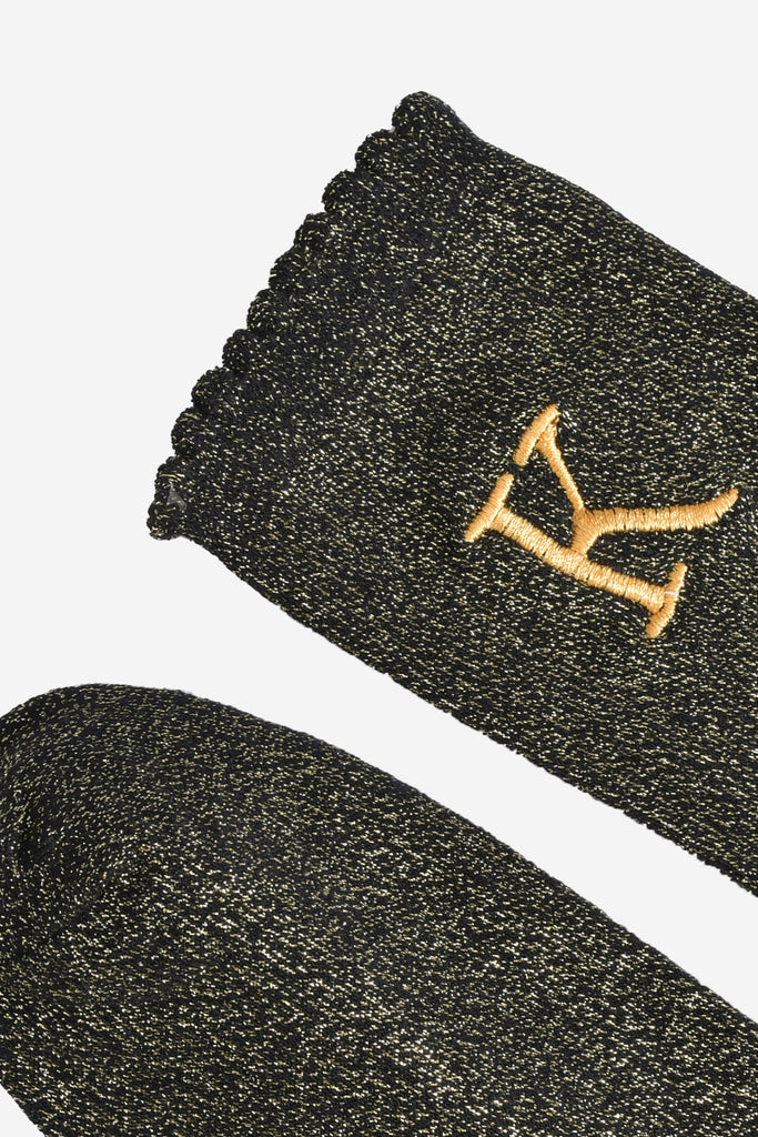 close up of the scalloped cuff on the socks, the toe is the same black and gold as the rest of the socks