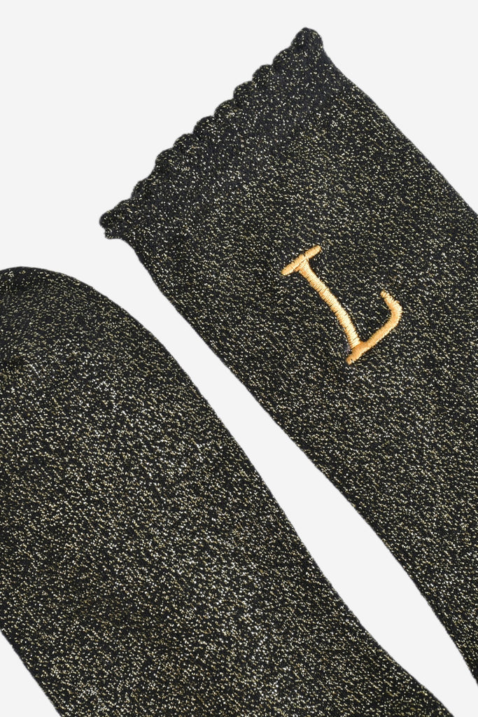 close up of the scalloped cuff on the socks, the toe is the same black and gold as the rest of the socks