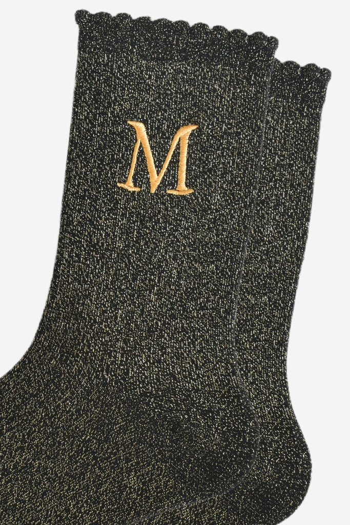 close up of the gold embroidered capital letter m on the ankle of the socks