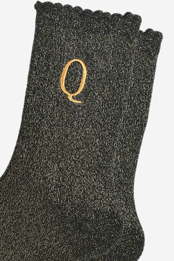 close up of the gold embroidered capital letter q on the ankle of the socks