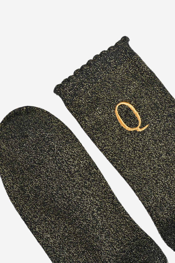 close up of the scalloped cuff on the socks, the toe is the same black and gold as the rest of the socks