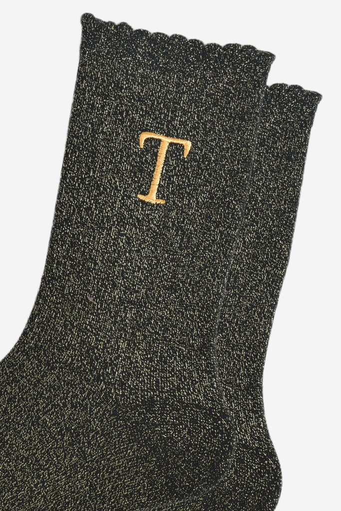 close up of the gold embroidered capital letter t on the ankle of the socks