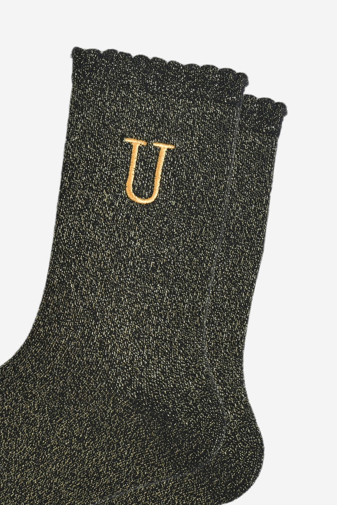 close up of the gold embroidered capital letter u on the ankle of the socks