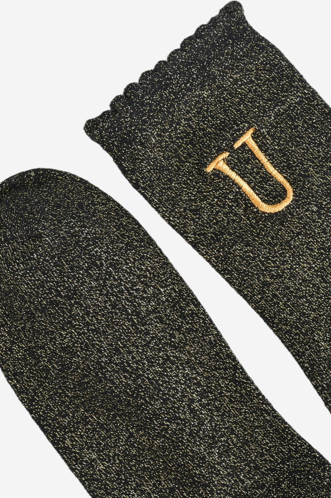 close up of the scalloped cuff on the socks, the toe is the same black and gold as the rest of the socks