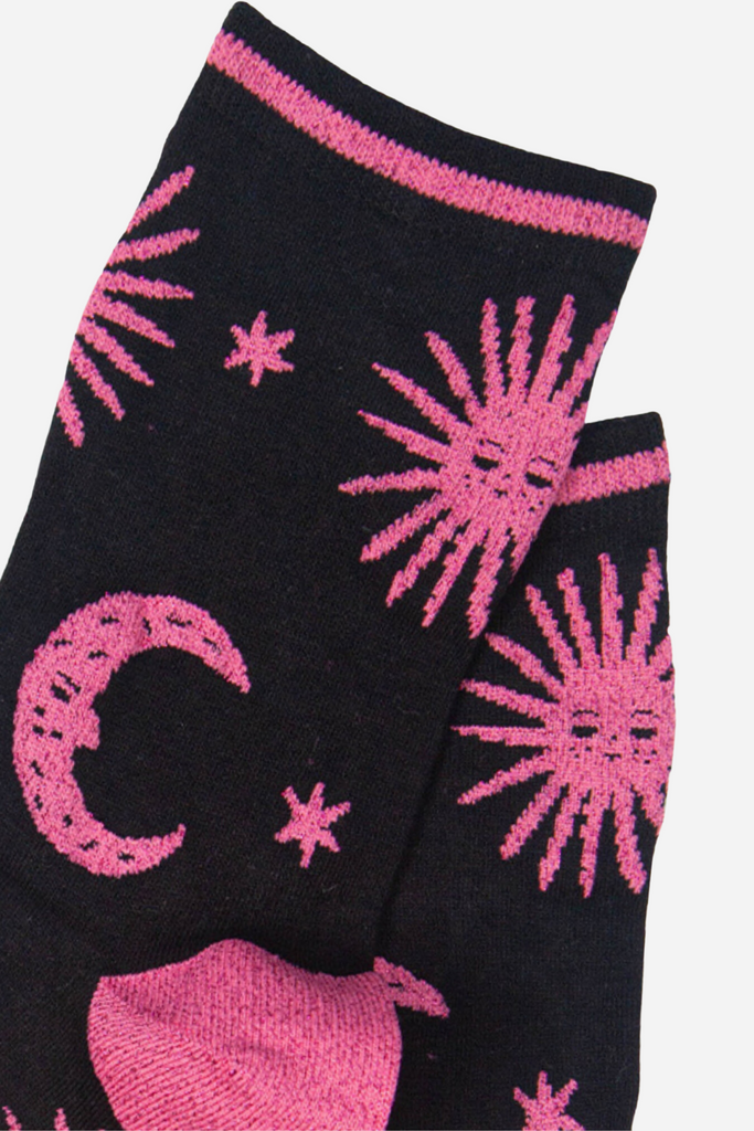 close up of the pink glitter sun and moon pattern on the black bamboo socks