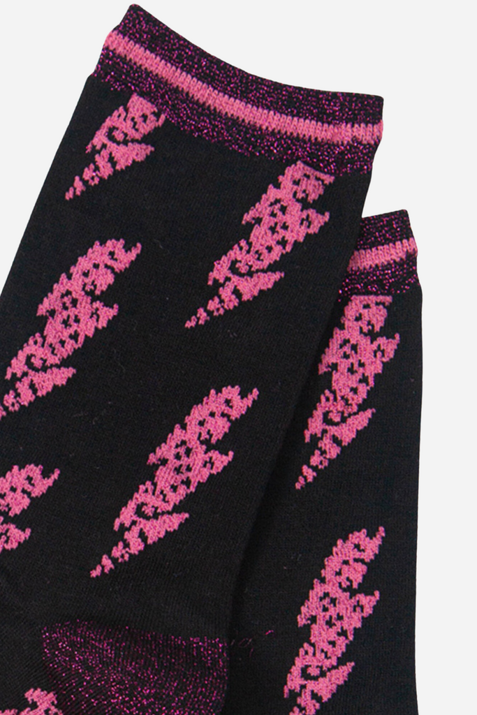 close up of the pink glitter lightning bolt pattern on the black bamboo socks