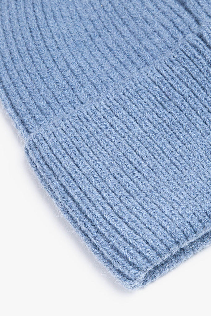 close up of the brim of the denim blue knitted beanie hat, showing the ribbed design