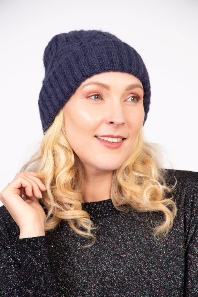 model wearing a navy blue cable knit winter beanie hat