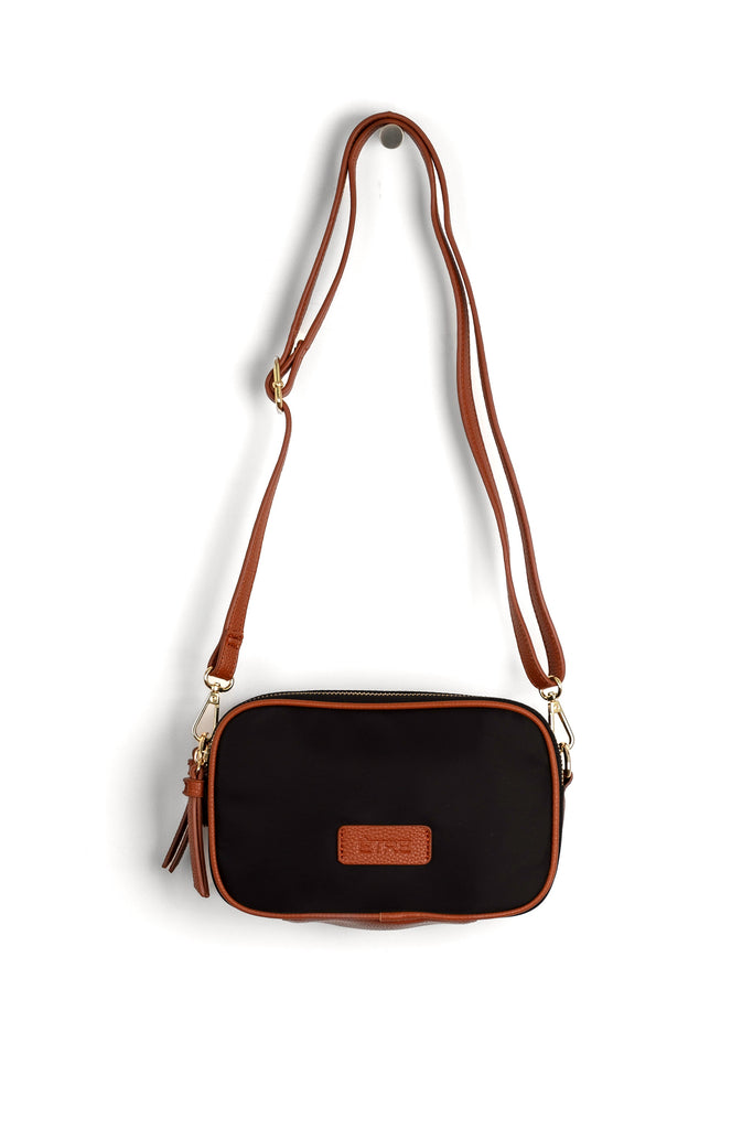 black crossbody bag with tan faux leather accents and a detachable strap