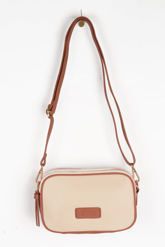 cream crossbody bag with tan faux leather accents and a detachable strap