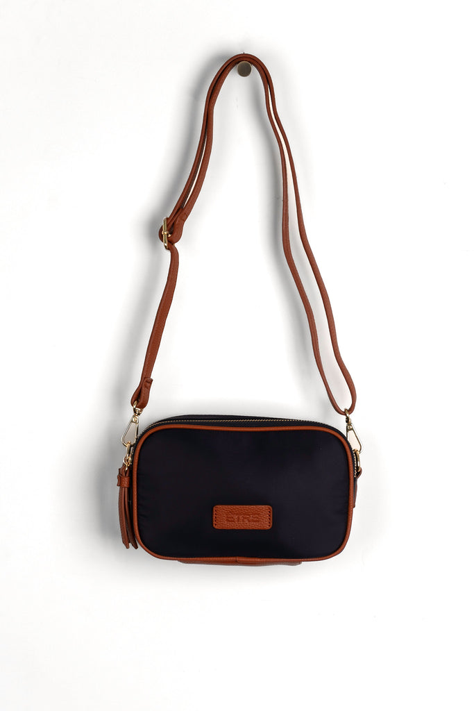 navy blue crossbody bag with tan faux leather accents and a detachable strap