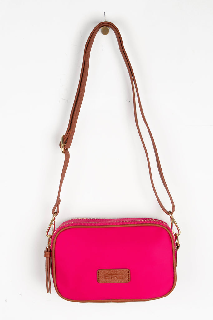 fuchsia pink crossbody bag with tan faux leather accents and a detachable strap